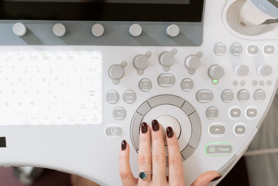 Hand operating a high-tech ultrasound control panel in a medical facility.